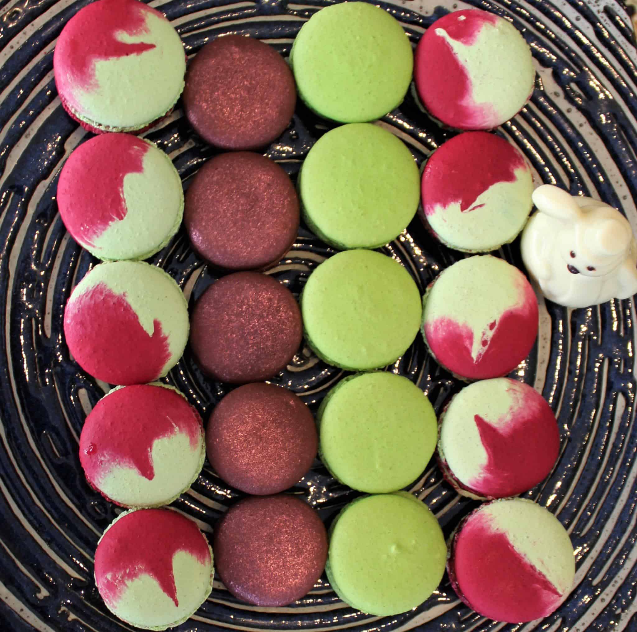 four rows of cocolorful macarons on a plate.