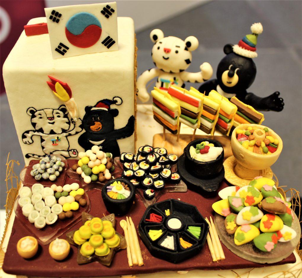 One of the amazingly detailed cakes from the Salon: the 2018 Olympic mascots sitting down to a Korean feast next to the Korean flag