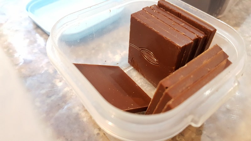 Thin chocolate squares stored in a plastic container.