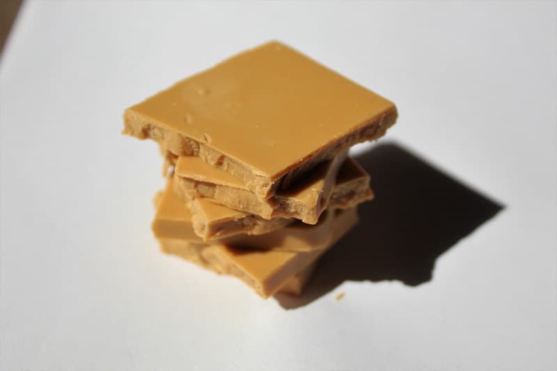 A rich piece of blonde chocolate (caramelized white chocolate), showcasing its golden hue and smooth texture.