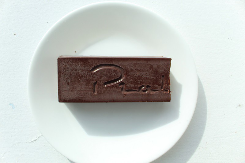 dark chocolate bar filled with a smooth pistachio butter on a white background.