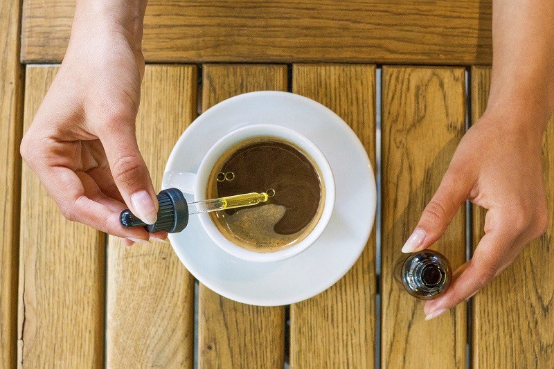 CBD tincture being added to a cup of coffee, enhancing the drink with the benefits of CBD.