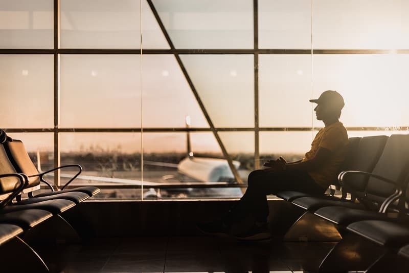 person sitting in shadow with airport in background.