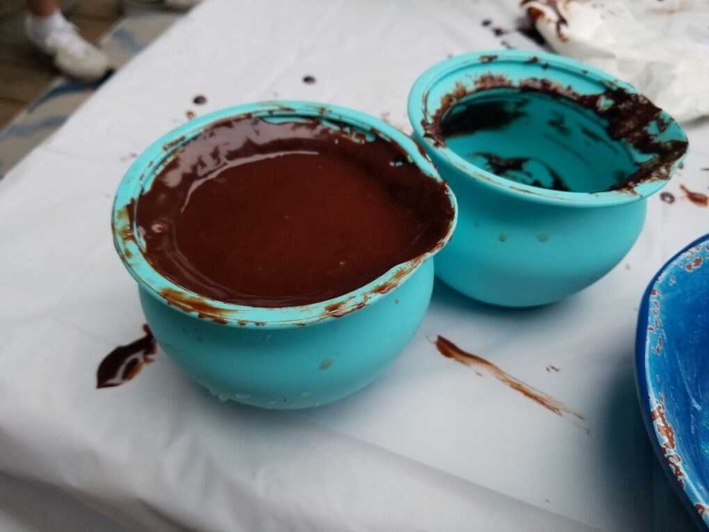 turquoise silicone containers of dark chocolate melted in the microwave, on a white table.