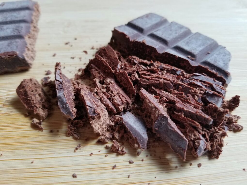 chopped bar of chocolate on a wooden cutting board.