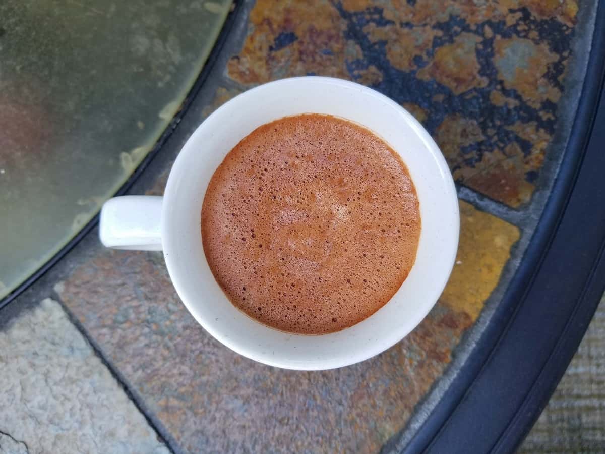 hot chocolate in a white cup on a tile background.