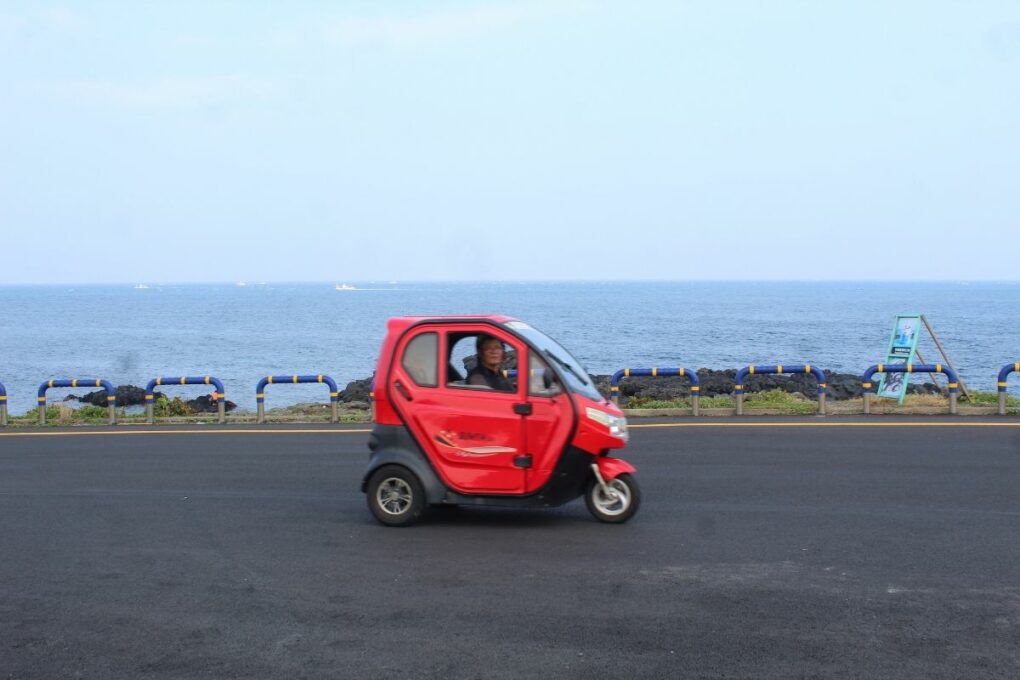 Small red electric car driving around Udo Island.