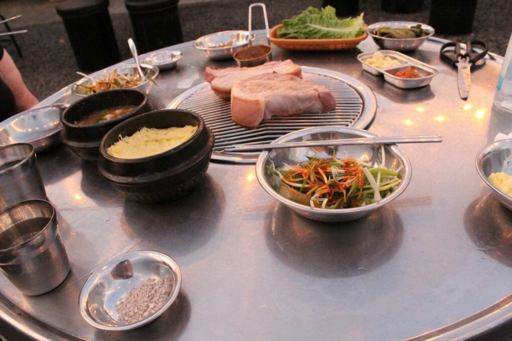 Black pork barbeque with various side dishes.