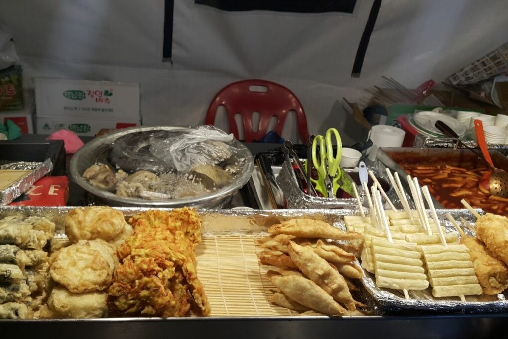 Assorted twigim and mandu placed on a tray in a street food stall. 