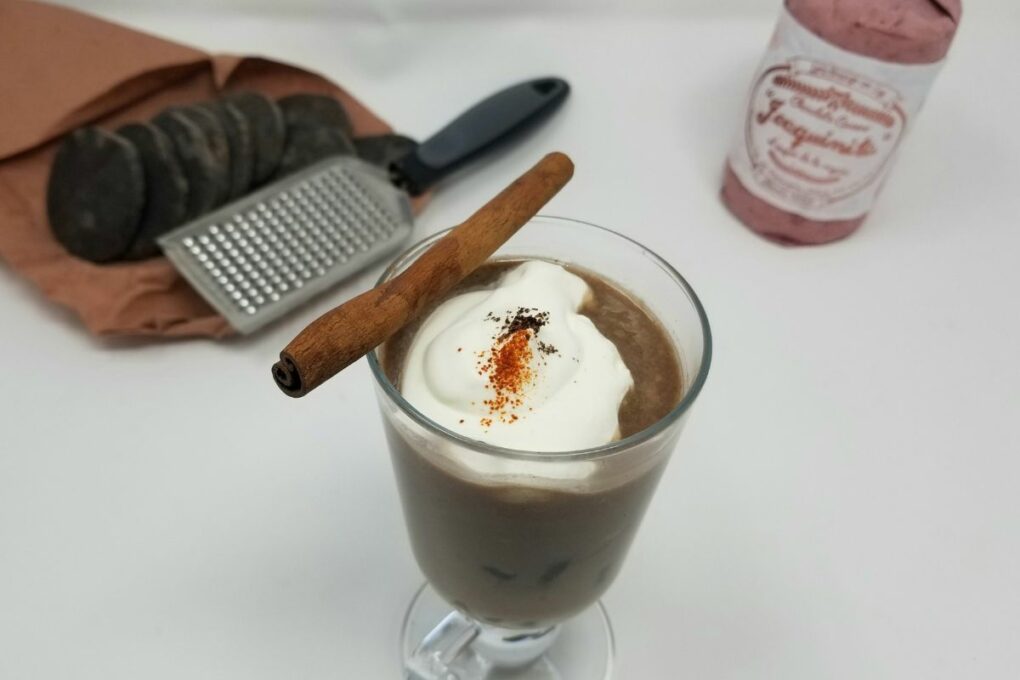 Cup of Mexican hot chocolate with whipped cream and cinnamon stick, served in a cozy mug, featured in the post "Classic Hot Fudge Sauce Recipe (With Cocoa Powder)."