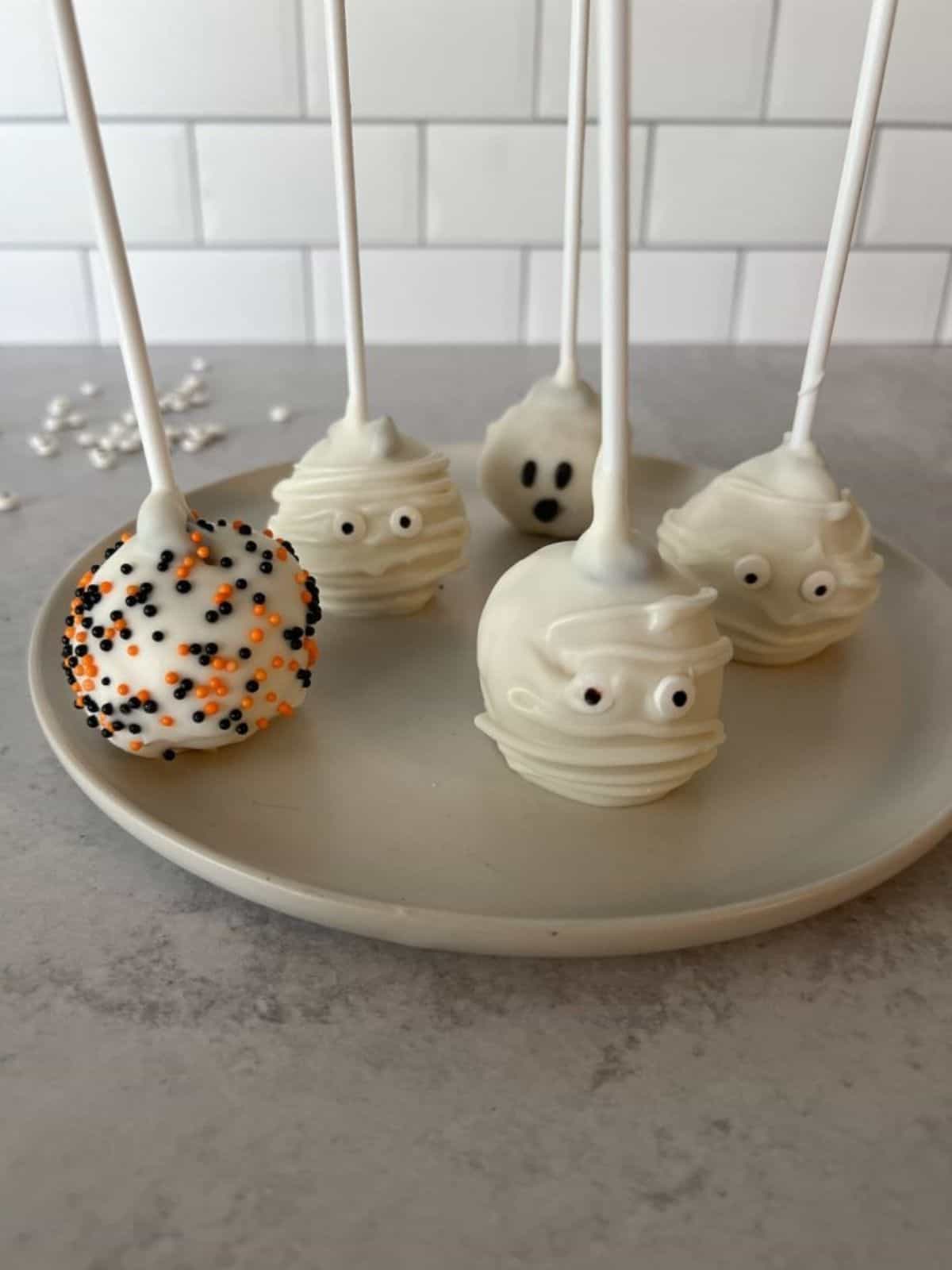 A plate of Halloween cake pops decorated with spooky designs, perfect for Halloween dessert ideas and festive celebrations.