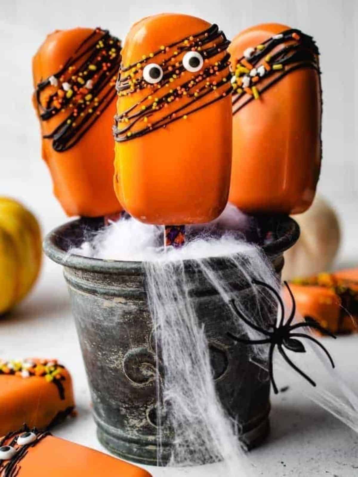 Festive Halloween cakesicles decorated with spooky designs, ideal for Halloween dessert ideas and party treats.