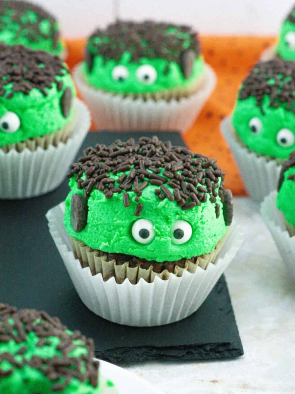 Frankenstein Cupcakes decorated with spooky green frosting, and candy eyes, perfect for Halloween dessert recipes.