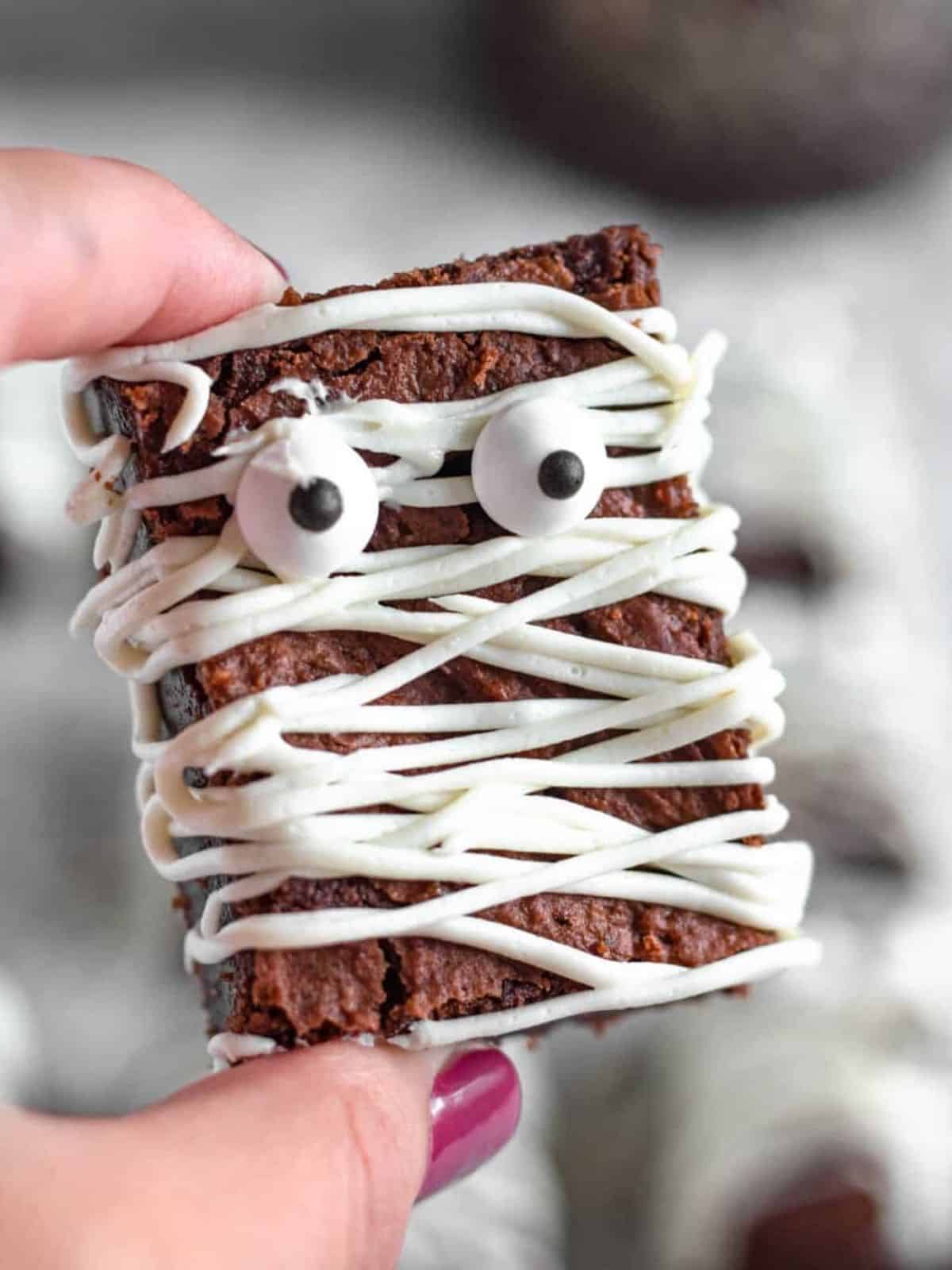 Mummy brownies decorated with white icing and candy eyes, perfect for a Halloween dessert.