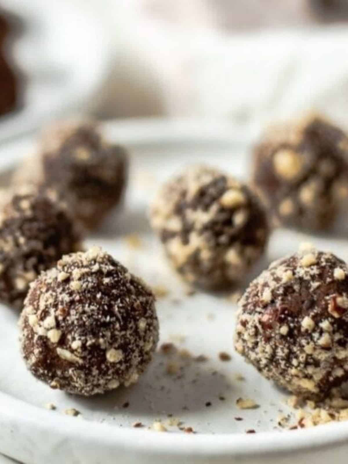 Chocolate Hazelnut Energy Balls covered with hazelnuts on a plate.