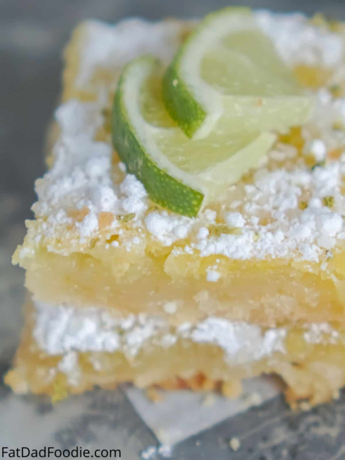Lime Bars topped with powdered sugar and lime.