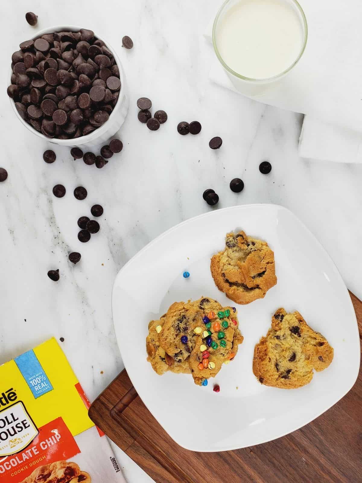 three cookie pieces with different toppings. served with chocolate chips and a glass of milk for dipping.