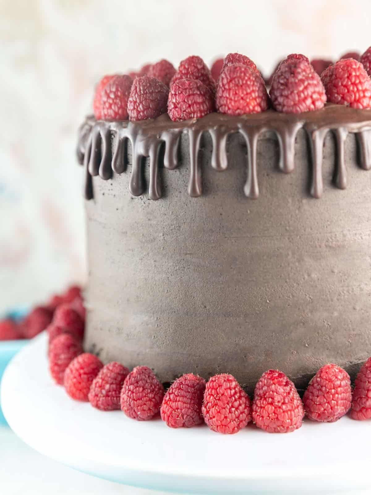 Layers of Chocolate Cake encased in Chocolate Buttercream with dripped Chocolate Ganache and Fresh Raspberries