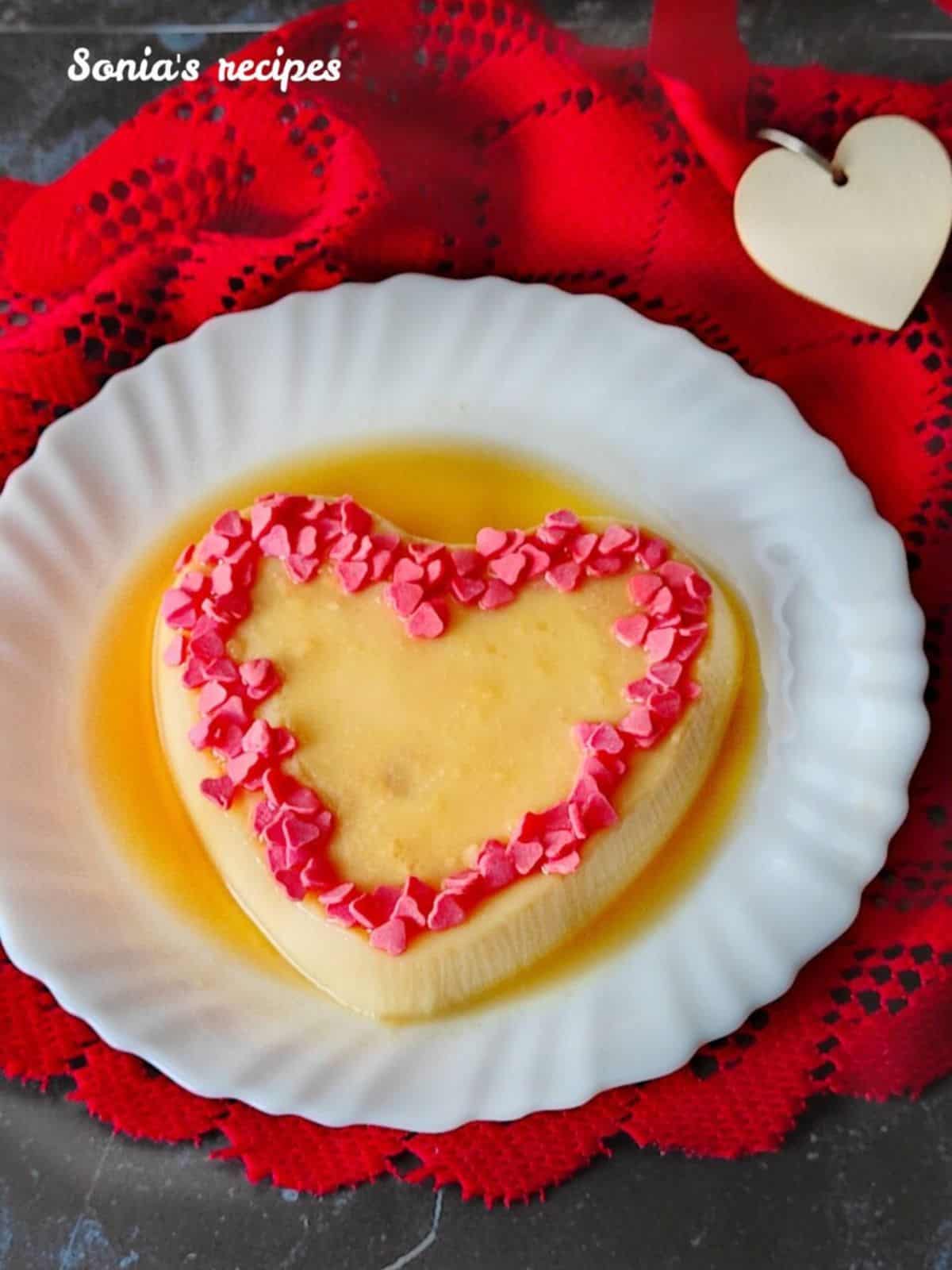 Sweet and decadent vanillla pudding heart with caramel sauce topped with pink confetti hearts