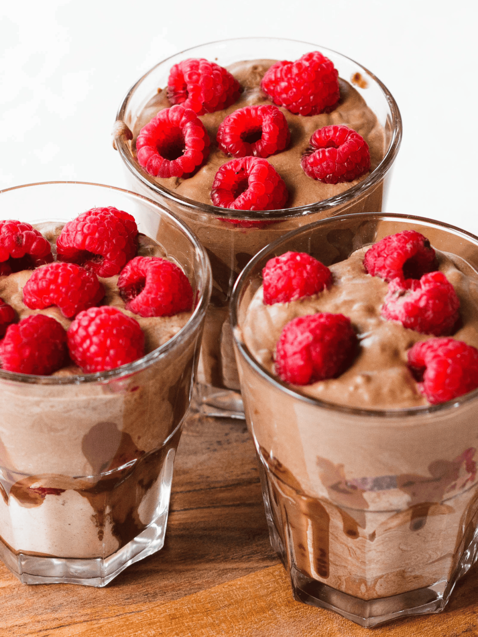 a tempting coconut chocolate pudding in a glass dessert dish, topped with some fresh raspberries.