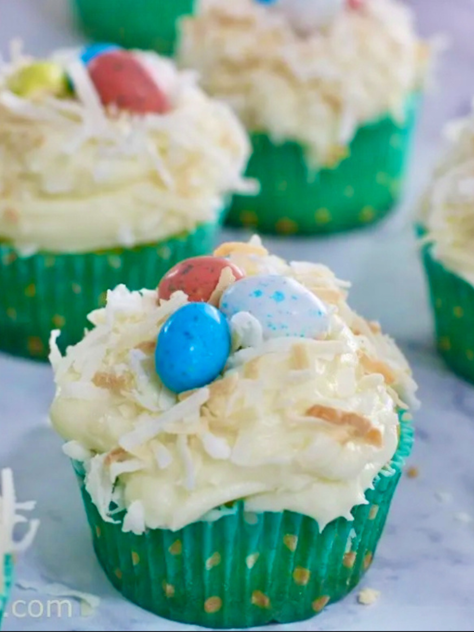 delicious coconut cupcakes topped with creamy coconut frosting, shredded coconut, and some Easter eggs.