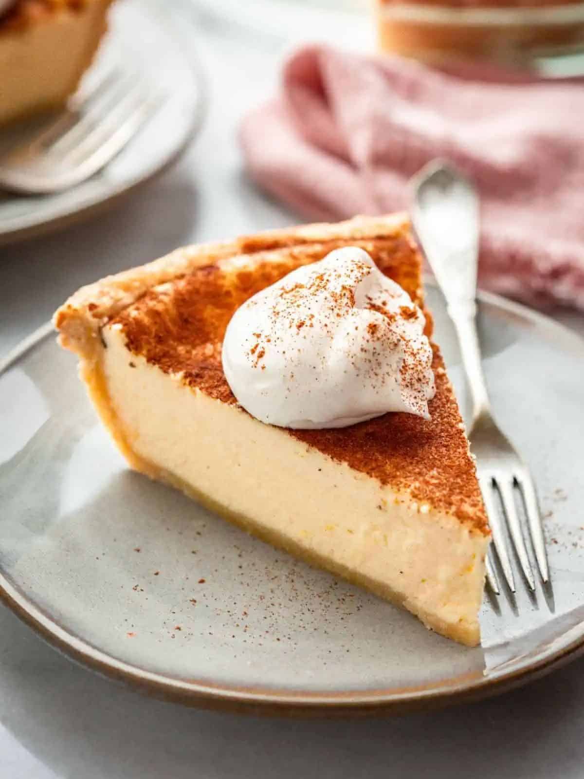 a tempting Italian ricotta pie with a golden, flaky crust, adorned with a dusting of cocoa and whipped cream.