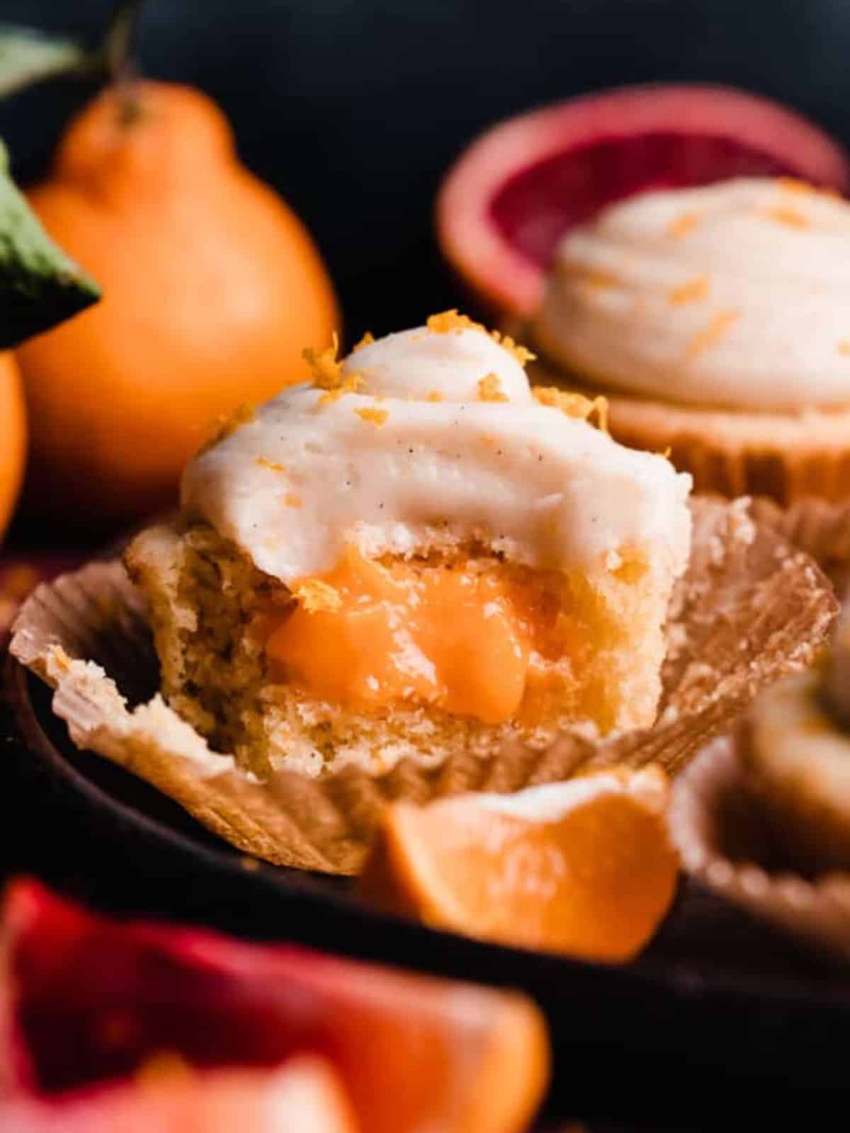 orange creamsicle cupcake with orange filling, topped with white frosting and orange zest.
