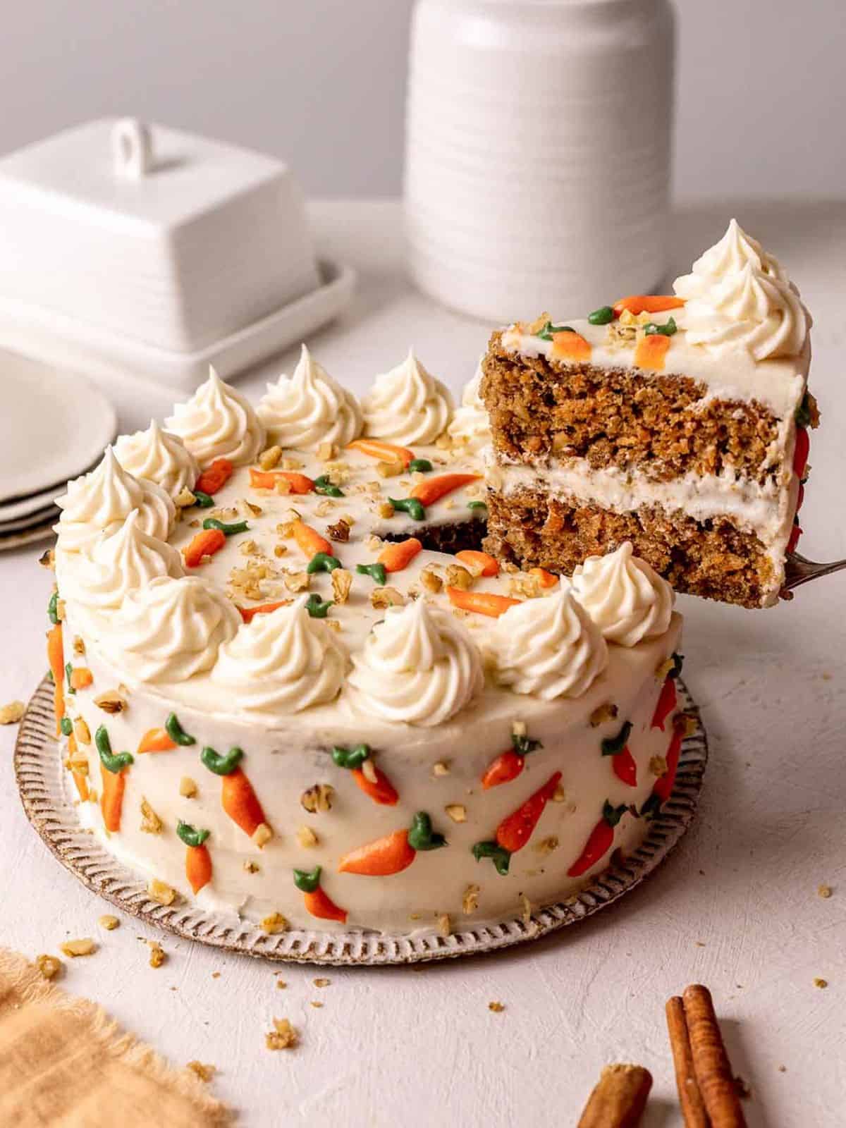 moist vegan carrot cake topped with creamy frosting, garnished with carrots and nuts.