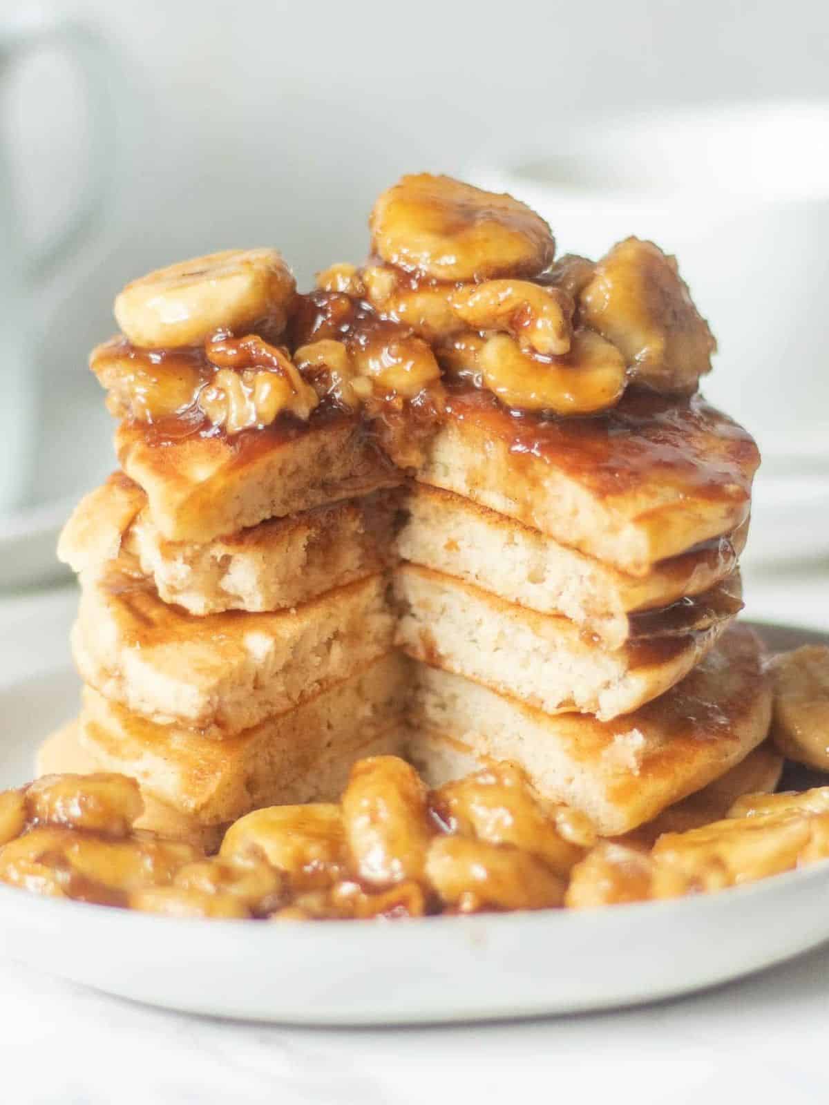 stack of golden banana foster pancakes topped with caramelized bananas.