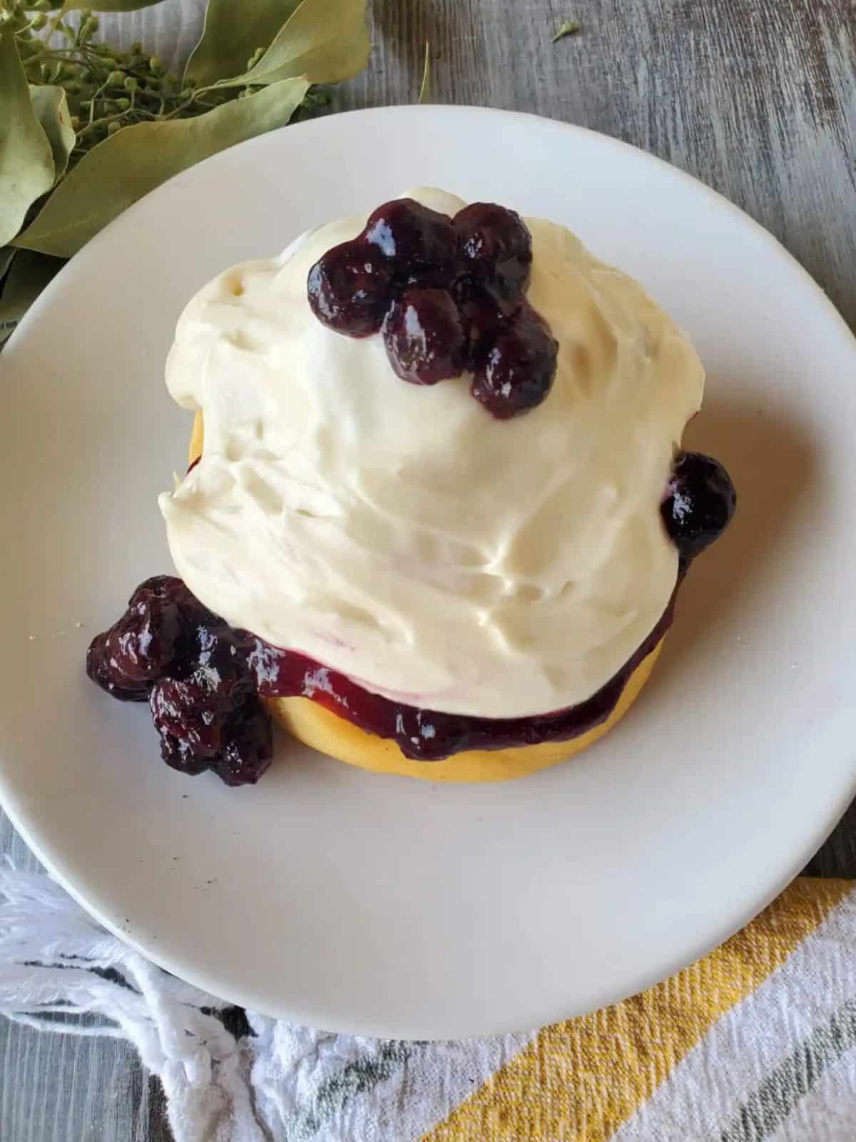 homemade blueberry cinnamon rolls topped with a generous cream cheese frosting and juicy blueberries.