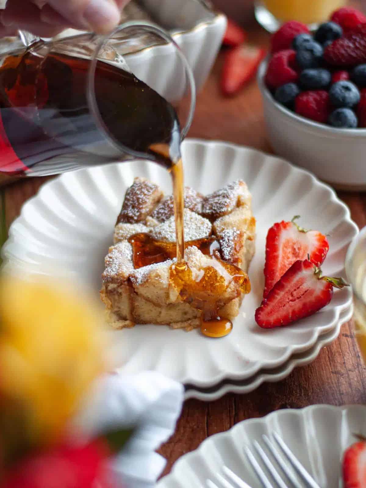 golden-brown slice of brioche French toast casserole with fresh berries and a drizzle of maple syrup.