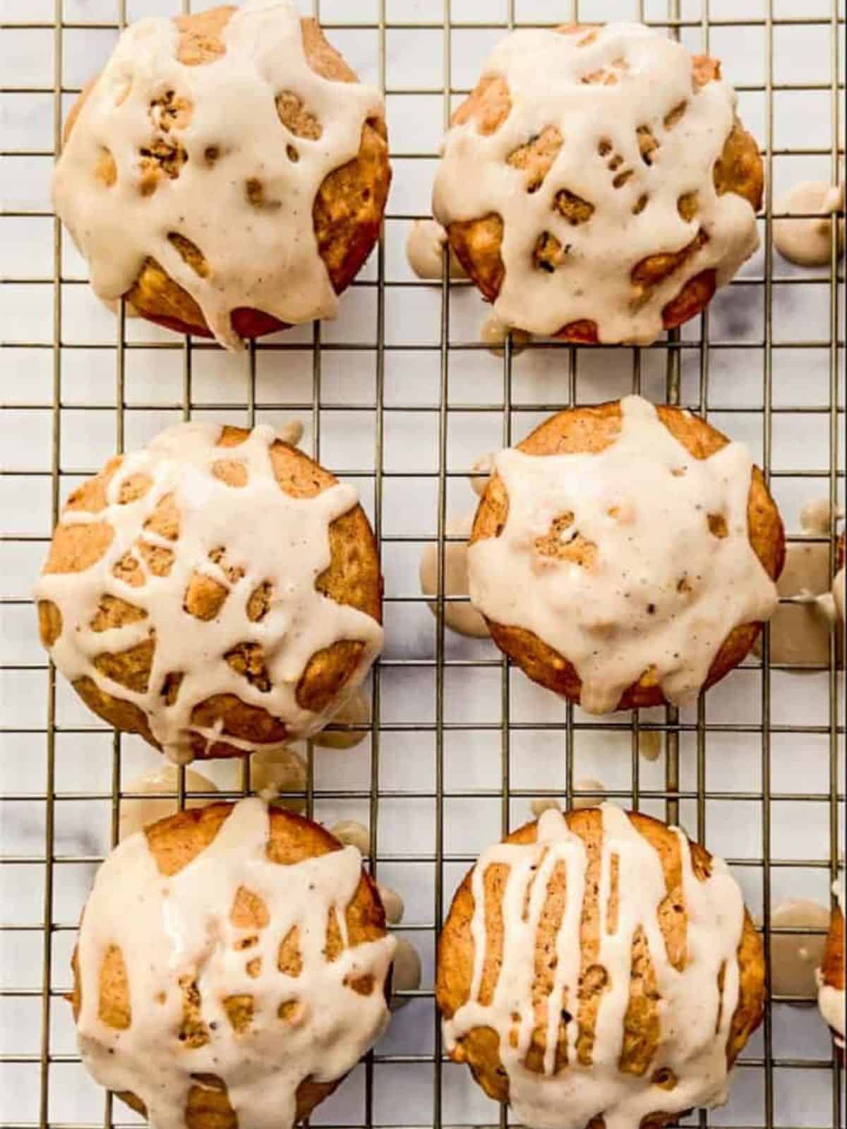 freshly baked chai spiced banana muffins on a baking tray, topped with glaze.