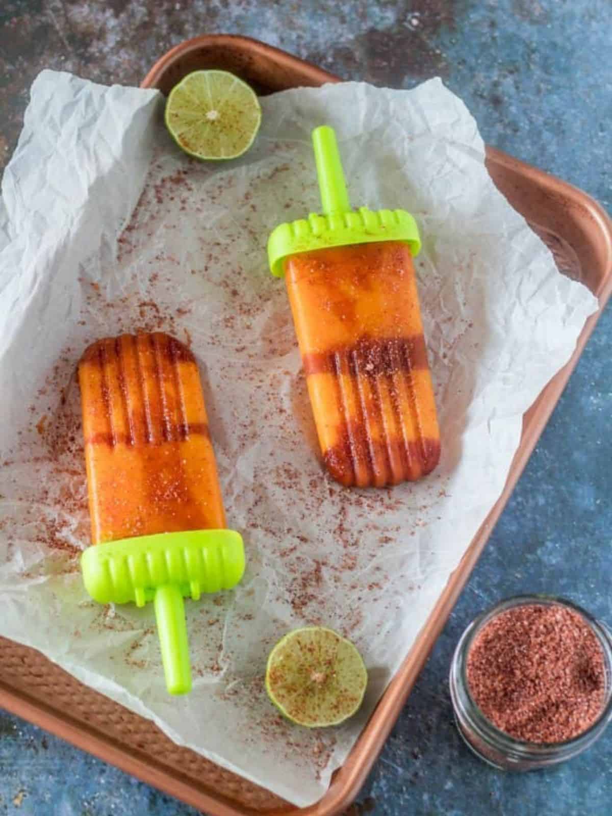 boozy mangonada paletas featuring the flavors of mango, tequila, orange liqueur, agave nectar, lime juice, chamoy, and tajin.