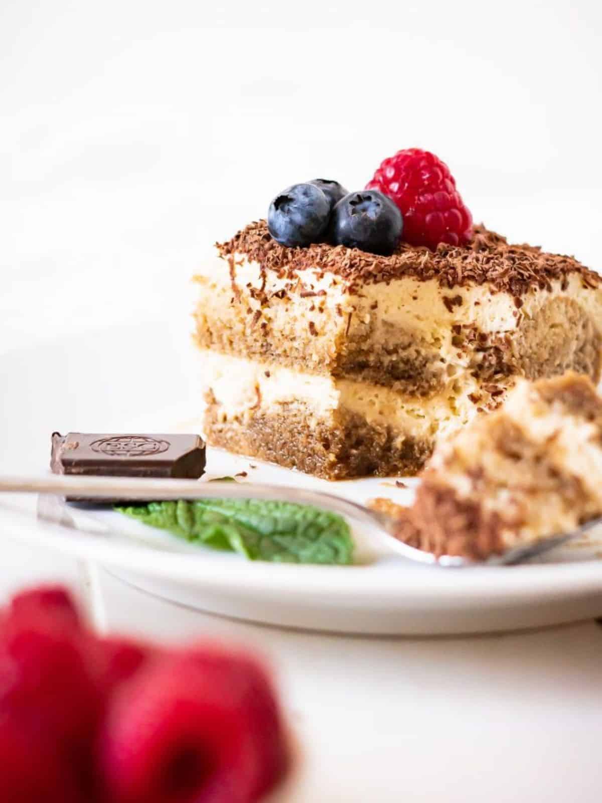 dairy-free tiramisu with layers of creamy mascarpone filling and coffee dipped ladyfingers, topped with fresh berries and shaved dairy-free chocolate.