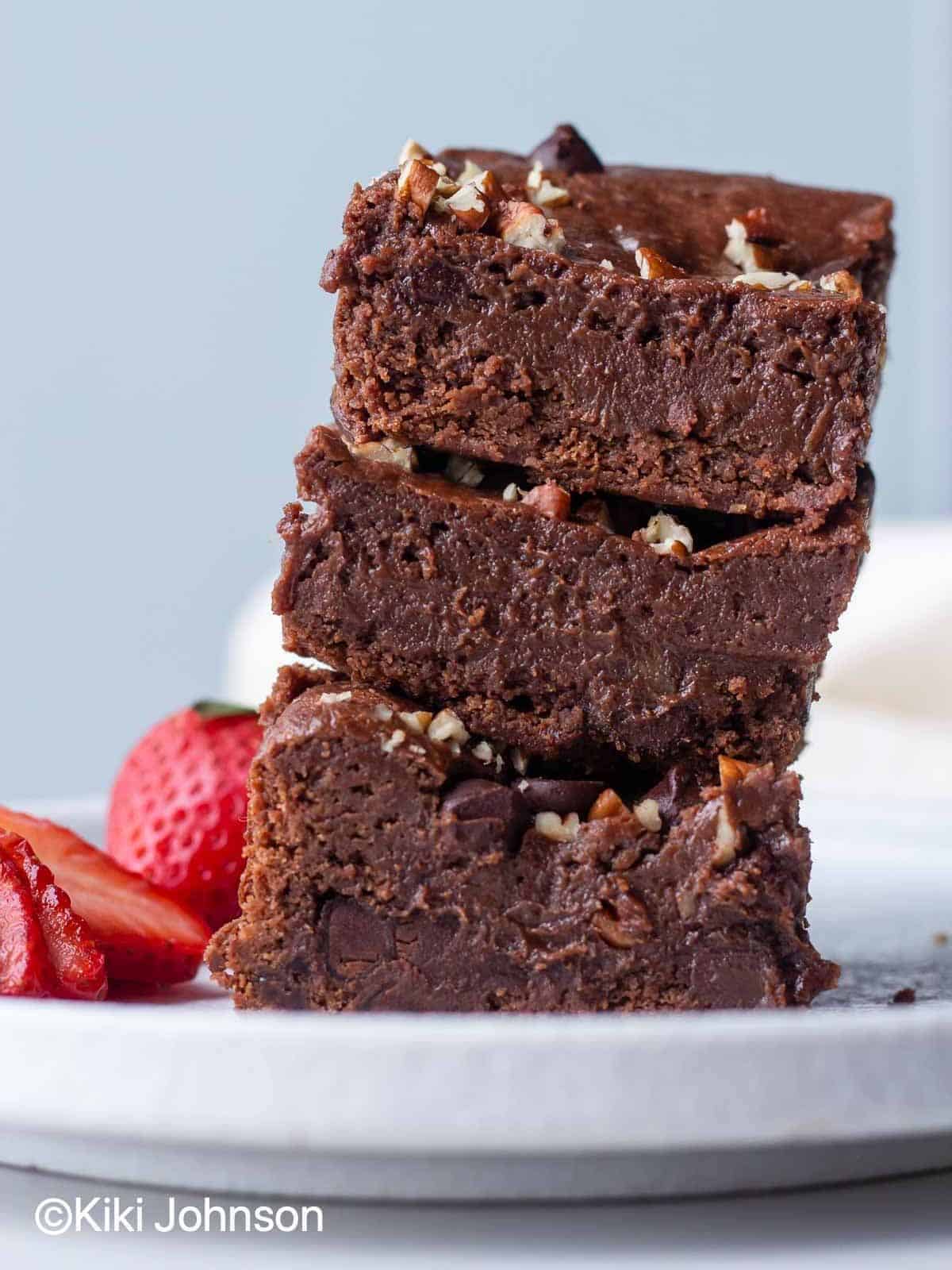 fudgy eggless Nutella brownies featuring a shiny thin crust on top, bursting with Nutella spread and sprinkled with nuts and chocolate chips.