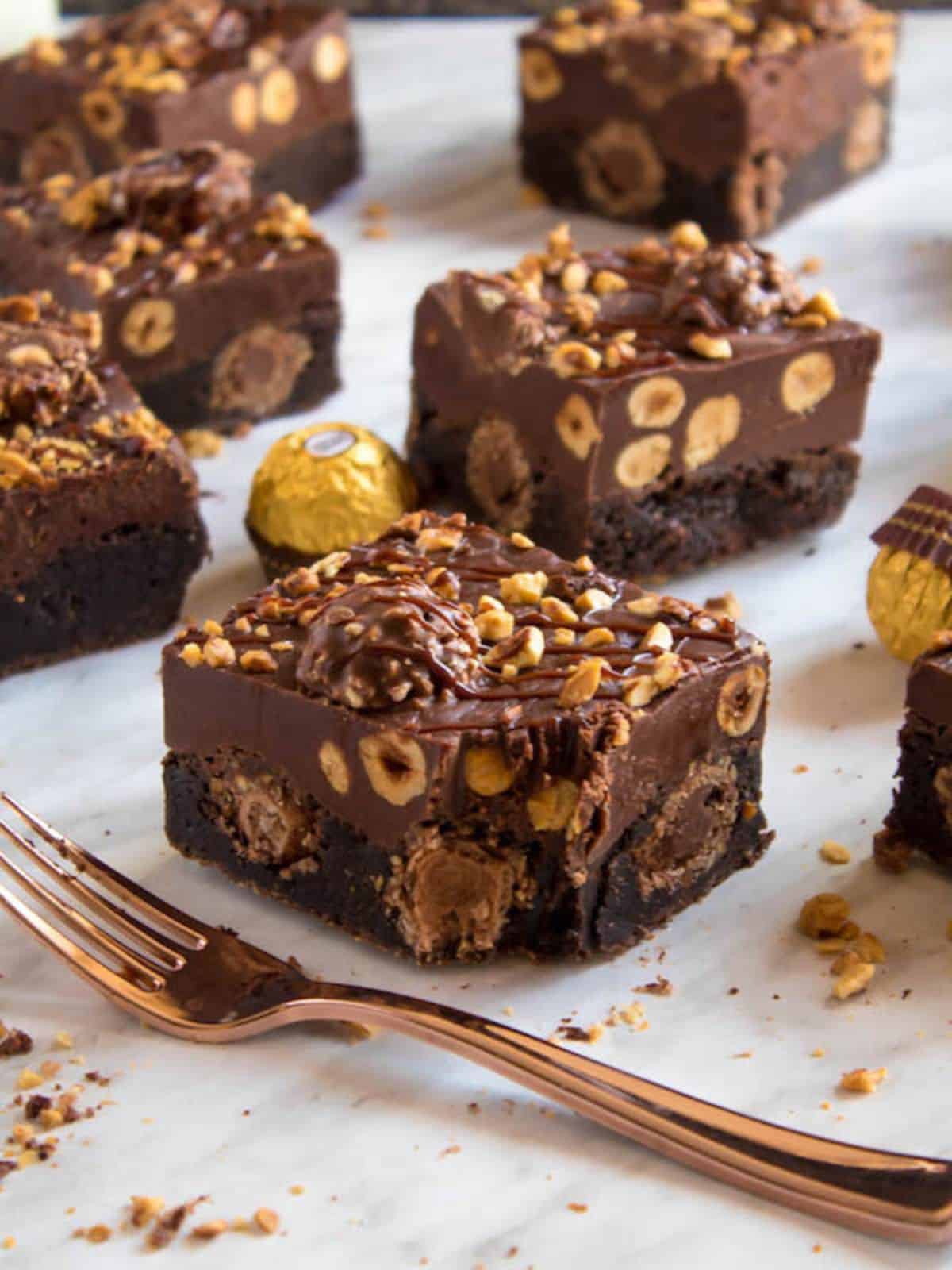 Ferrero Rocher fudge brownies topped with creamy Nutella fudge filled, Ferrero Rocher chocolates, and roasted hazelnuts.