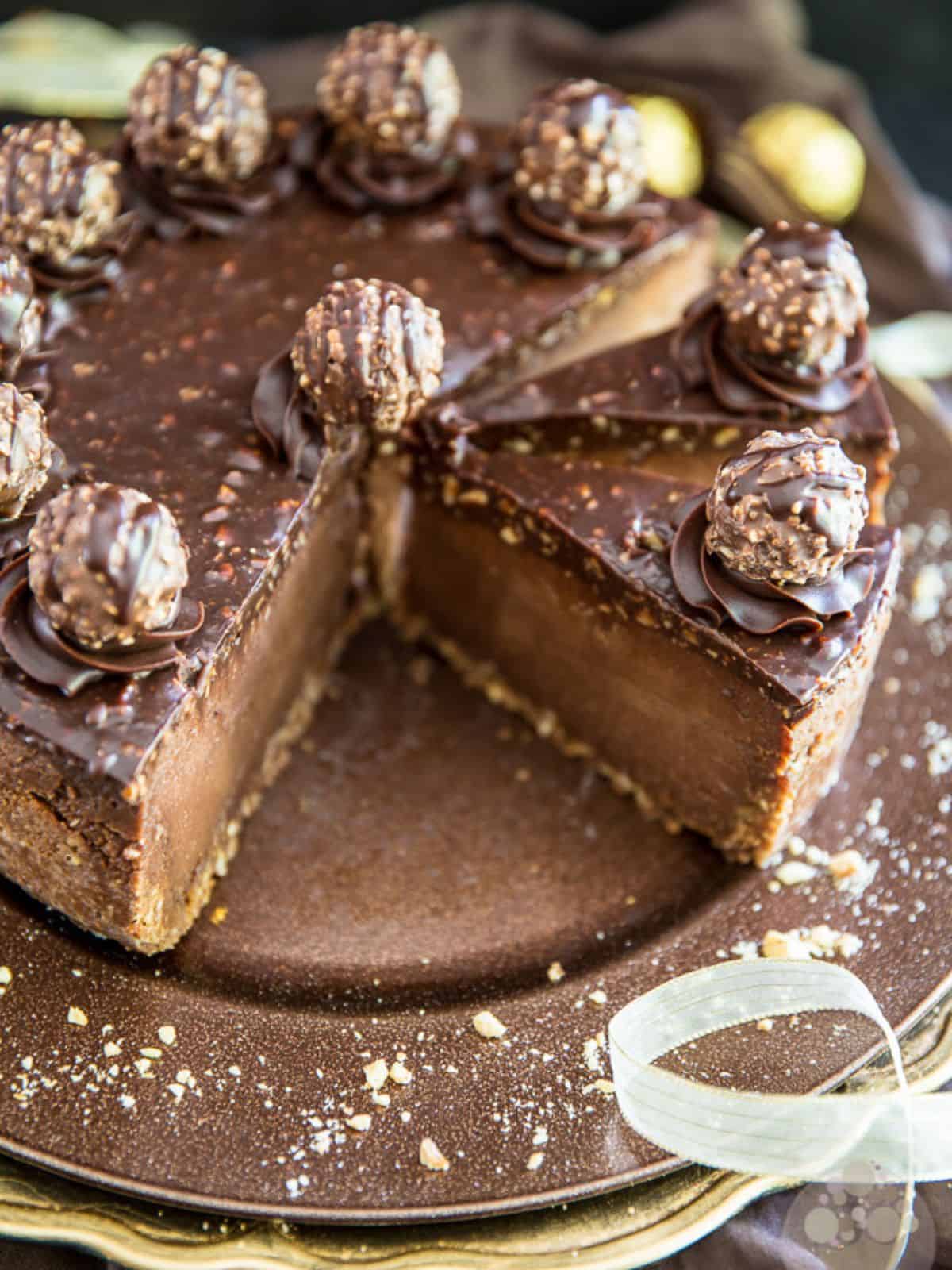 Ferrero Rocher Nutella cheesecake made with crunchy crust, cheesecake filling, hazelnut spread, and melted chocolate, topped with Ferrero Rocher-like truffles and Nutella ganache.