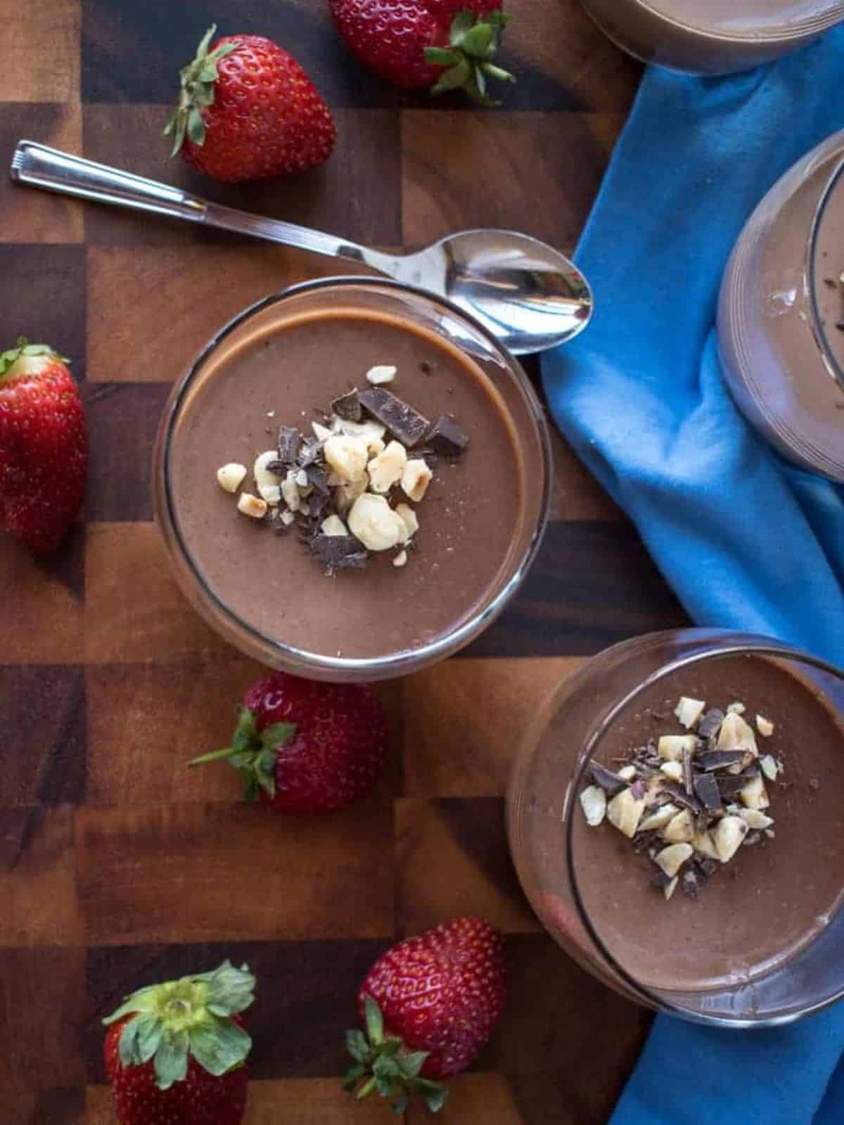 decadent and chocolatey Nutella panna cotta in a glass, topped with sliced chocolates and nuts.