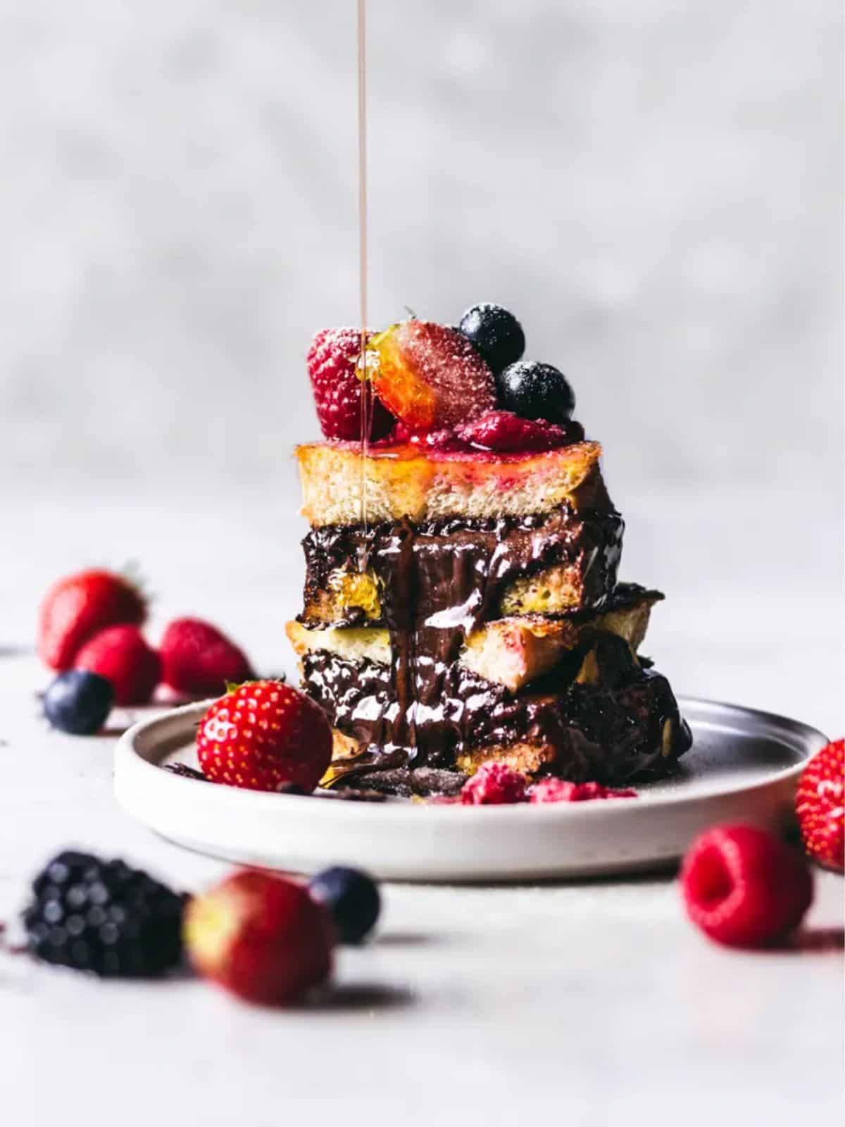 slices of French toast stuffed with Nutella and dark chocolate, topped with fresh berries.