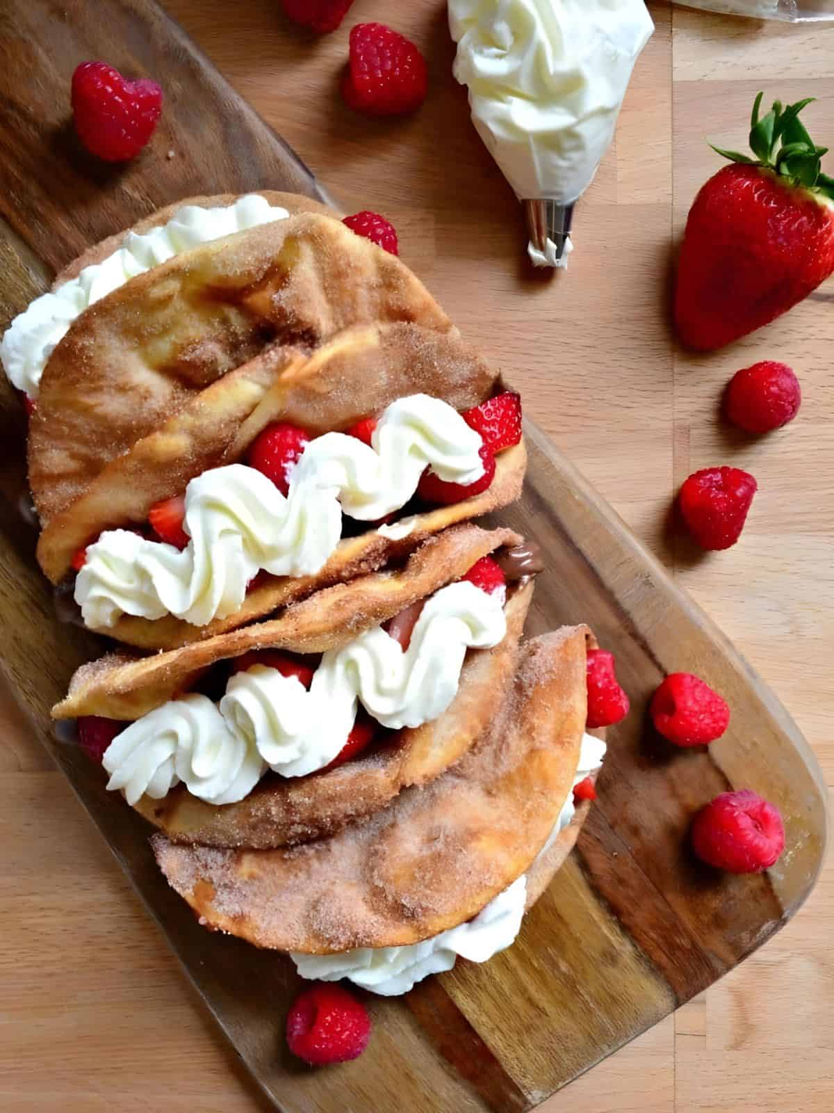 strawberry raspberry Nutella dessert tacos made with cinnamon sugar-coated flour tortillas, filled with fresh juicy berries, creamy Nutella spread, and topped with whipped cream.