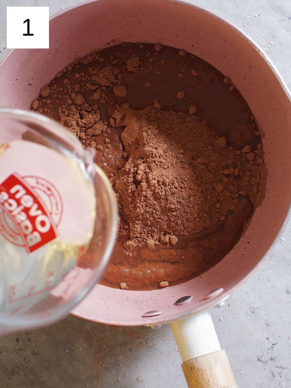 Pouring water onto cocoa powder in a saucepan.