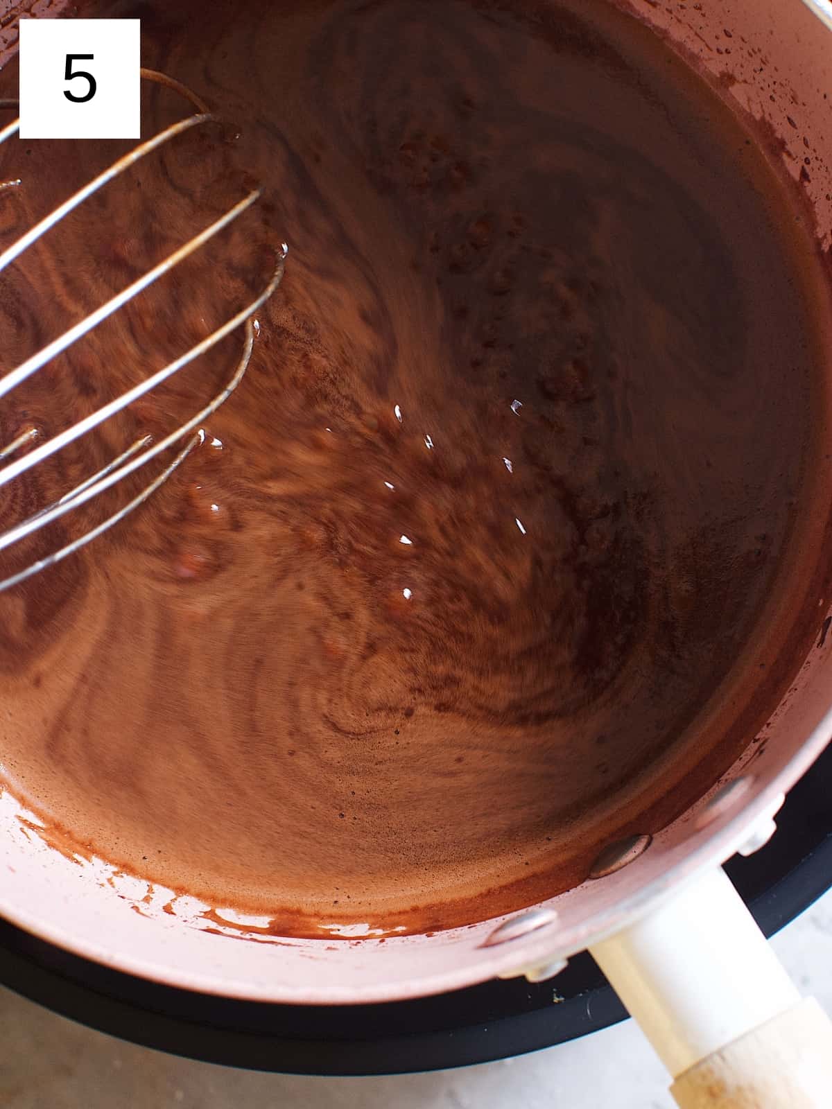 Stirring soft boiled cocoa mixture in a heated sauce pan.