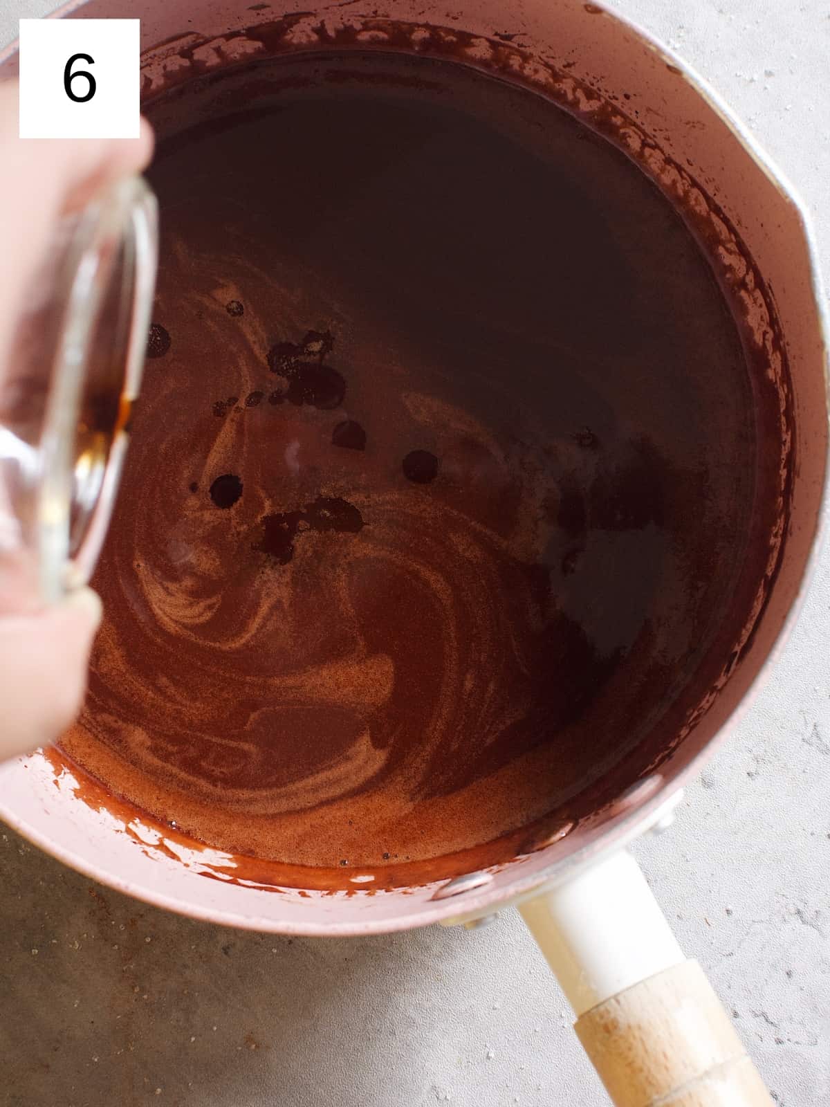 Adding vanilla extract to the cocoa mixture in a sauce pan removed from heat.