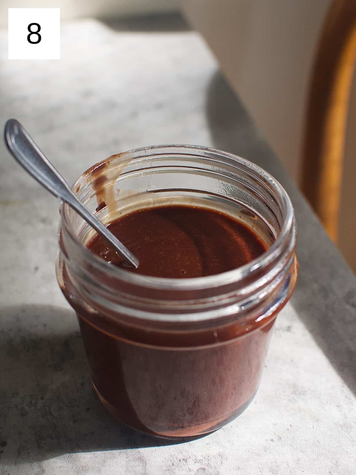 Cocoa syrup in a glass jar with a table spoon.