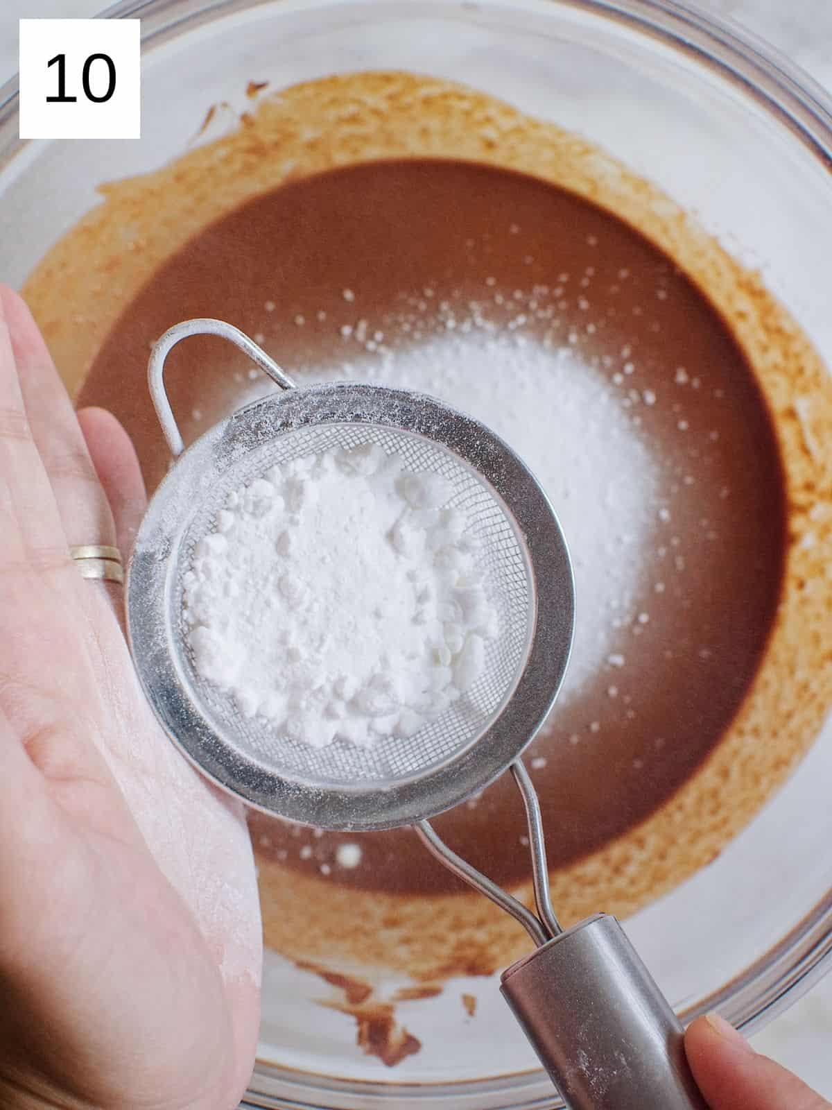 Icing sugar on a sift being poured in the cocoa butter.