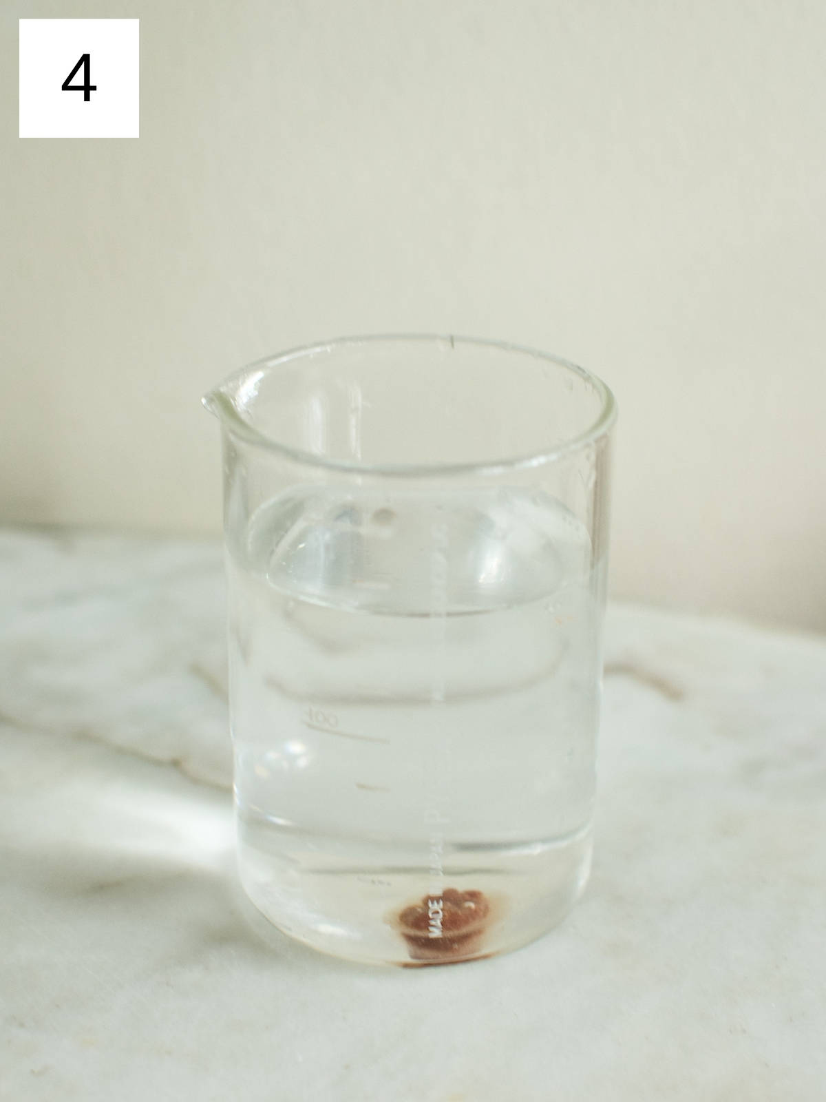 A droplet of cocoa mixture in a glass of room temperature water.