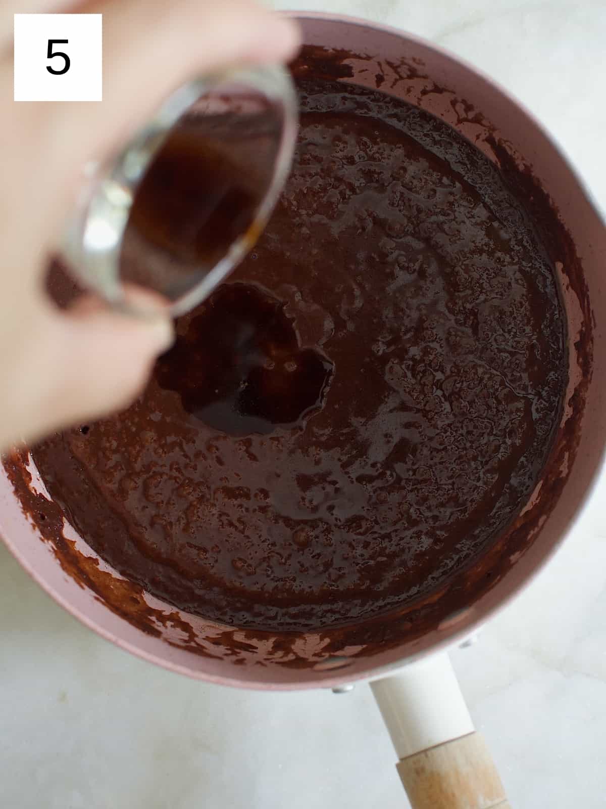 Adding vanilla extract to the cocoa mixture in a nonstick pot that has been removed from heat.