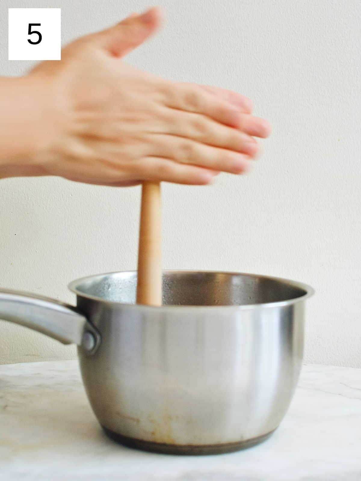 mixing the melted tableya in a pot with a batirol.