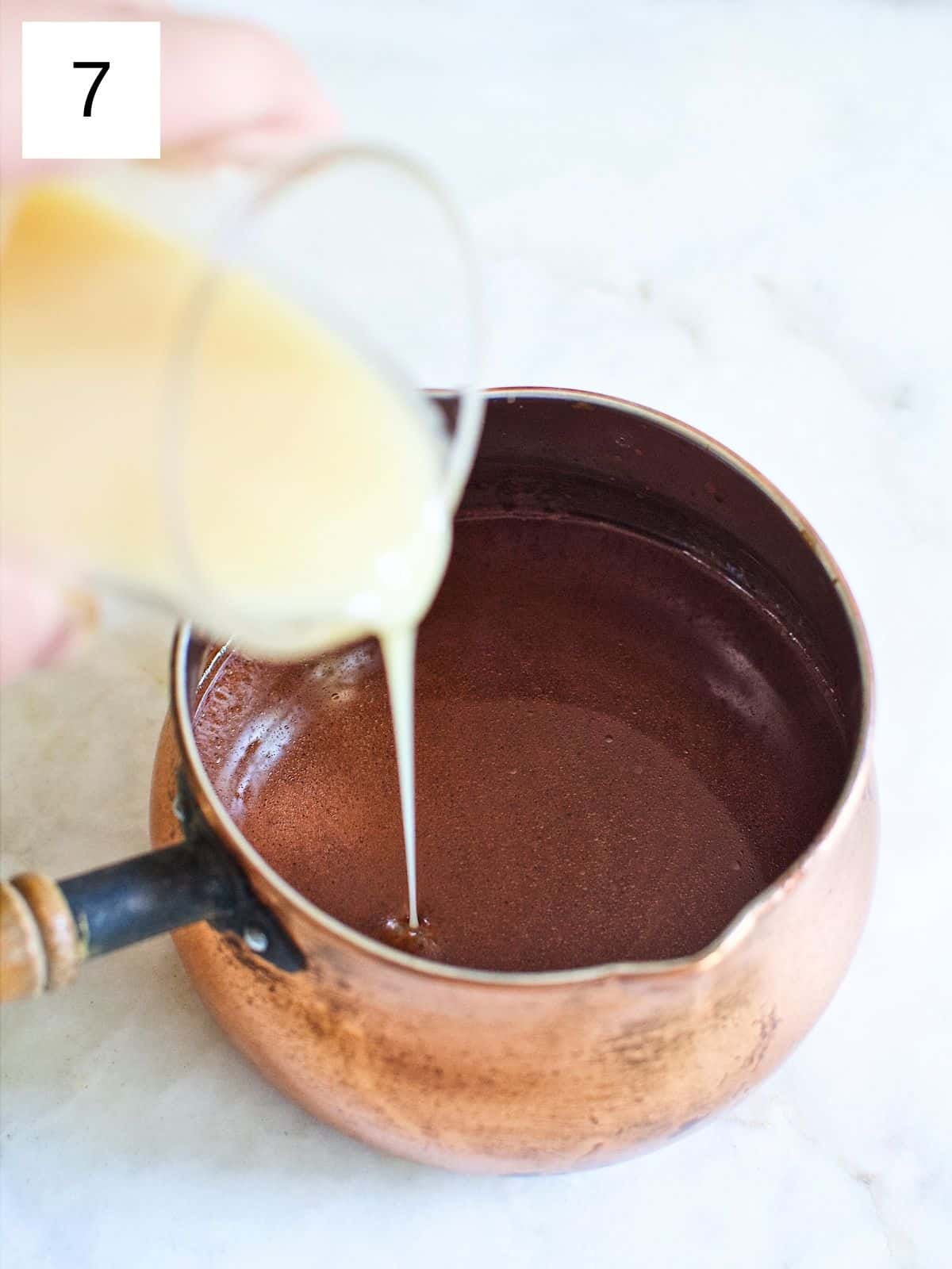 pouring condensed milk in a pot of melted tableya.