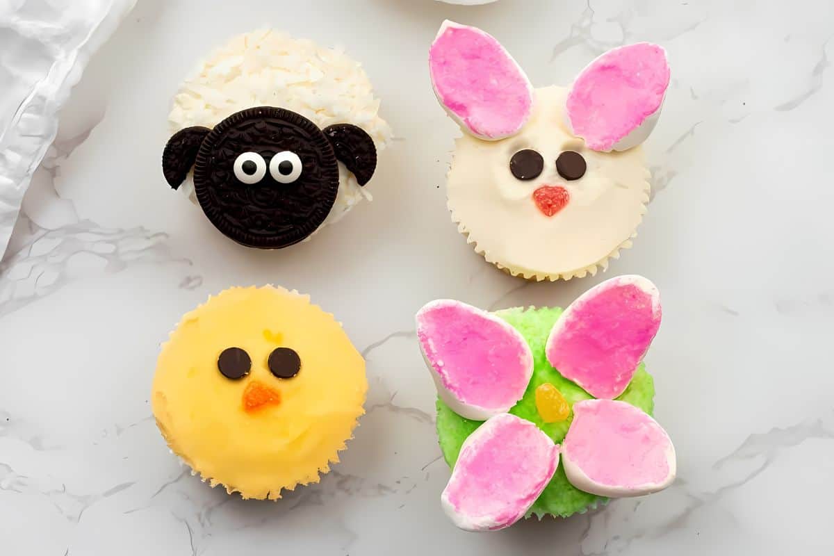 Easter-themed cupcakes decorated to look like a sheep, bunny, chick, and a flower.